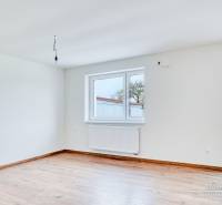 Ein geräumiges Zimmer in einem Einfamilienhaus mit einem Holzboden und großen Fenstern.