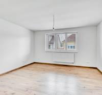 Ein leerer Raum in einem Einfamilienhaus mit Holzboden und weißen Wänden.