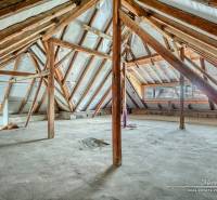 Dachboden eines Einfamilienhauses mit Holzbalken und unbehandeltem Boden.