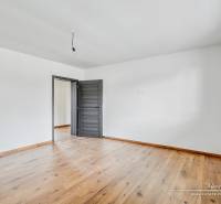 Ein Zimmer in einem Einfamilienhaus mit weißen Wänden und einem Boden in Holzoptik.