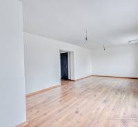 Ein geräumiges Zimmer in einem Einfamilienhaus mit Holzboden und weißen Wänden.