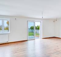 Helles Zimmer mit Holzboden in einem Einfamilienhaus, große Fenster, Zugang zur Terrasse.