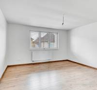 Ein Zimmer mit weißen Wänden und einem Boden in Holzoptik in einem Einfamilienhaus.