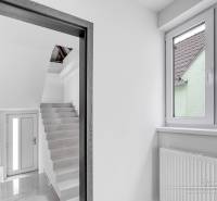 Innenraum eines Einfamilienhauses mit weißen Wänden, Treppe und großem Fenster.
