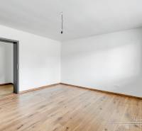 Ein Zimmer mit weißen Wänden und einem Boden in Holzoptik in einem Einfamilienhaus.