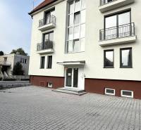 Das Gebäude in der Sadová-Straße in Senica mit weißer Fassade und gepflastertem Parkplatz.