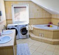 Badezimmer mit Badewanne, zwei Waschbecken, Waschmaschine und Trockner in einem Einfamilienhaus.