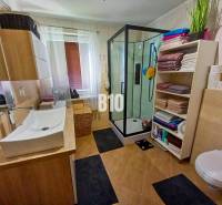 Ein Badezimmer in einem Einfamilienhaus mit Waschbecken, Duschkabine und einem Regal für Handtücher.