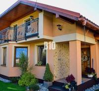 Ein Einfamilienhaus in Čierne mit Balkon, Steinfassade und gepflegtem Garten.