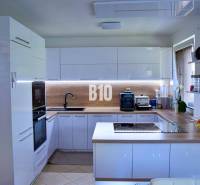 Eine Küche in einem Einfamilienhaus mit eingebauten Geräten, einem Kochfeld und einer Arbeitsplatte aus Holz.