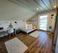 Kinderzimmer im Dachgeschoss eines Einfamilienhauses mit Bett, Tisch und Dekorationen.