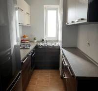 Küche in einer 3-Zimmer-Wohnung mit modernen Schränken, Herd, hellen Wänden, Keramikboden.