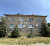 Ein Wohnhaus umgeben von Grünflächen in Bošany mit mehreren Satellitenschüsseln an der Fassade.