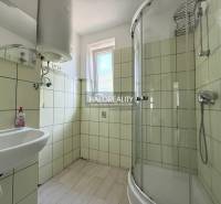 Badezimmer in einer 3-Zimmer-Wohnung mit Waschbecken, Duschkabine und Fenster.