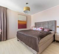 Schlafzimmer in einem Einfamilienhaus mit Bett, Bild, Lampe und Boden mit Holzdekor.