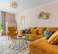 Wohnzimmer in einem Einfamilienhaus mit einem senffarbenen Sofa und einem Tisch auf einem Boden mit Holzdekor.