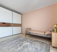 Ein Zimmer in einem Einfamilienhaus mit einem Metallbett, einem Schrank und einem Boden mit Holzdekor.