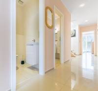 Der Flur im Einfamilienhaus mit hellen Fliesen, offene Tür zum Badezimmer, Spiegel an der Wand.