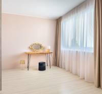 Helles Zimmer in einem Einfamilienhaus mit Schminktisch, goldenem Spiegel und Boden in Holzoptik.