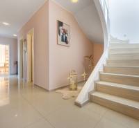 Ein Flur in einem Einfamilienhaus mit Fliesen, einer Treppe und Dekorationen an den Wänden.