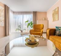 Wohnzimmer eines Einfamilienhauses mit bequemen Sesseln, dekorativen Pflanzen und einem Boden in Holzoptik.