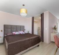 Schlafzimmer im Einfamilienhaus mit großem Bett, Kleiderschrank und Boden mit Holzdekor.