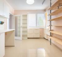 Innenraum eines Einfamilienhauses mit Regalen, Küchenzeile und großen Fenstern mit Rollläden.