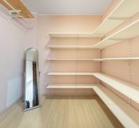 Ein Kleiderschrank im Einfamilienhaus mit Regalen, einem Standspiegel und einem Boden mit Holzdekor.