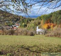 Eine Kirche umgeben von herbstlicher Natur in Záhrady, Hlboké nad Váhom mit Blick auf die Berge.