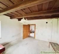 Innenraum eines Einfamilienhauses mit Holzdecke, weißen Wänden und einfacher Einrichtung.