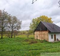 Ein Einfamilienhaus in Senohrad, umgeben von Bäumen und einem grasbewachsenen Grundstück unter einem bewölkten Himmel.