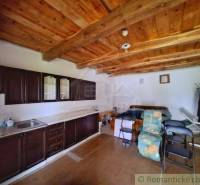 Eine Küche in einem Einfamilienhaus mit einer Holzdecke und einer Küchenzeile in dunkler Farbe.