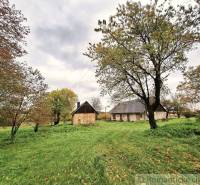 Ein weitläufiger Garten in Senohrad mit einem Einfamilienhaus und Bäumen auf einem grasbewachsenen Grundstück.
