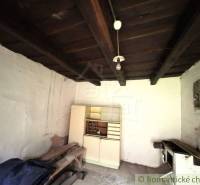 Innenraum eines Einfamilienhauses mit Holzbalkendecke, weißem Schrank und altem Herd.