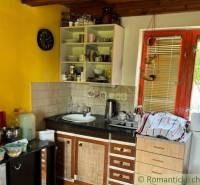 Küche in einer Hütte mit Holzdecke und gelber Wand, ausgestattet mit grundlegenden Geschirr.