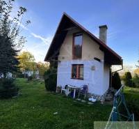 Eine Hütte in Sološnica mit einem gepflegten Garten, umgeben von Bäumen und klarem Himmel.