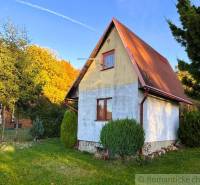Ein Ferienhaus in Sološnica, umgeben von Grün, mit einem Satteldach und gepflegtem Rasen.