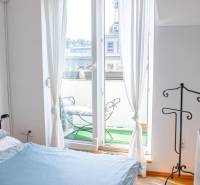 Schlafzimmer in einer 3-Zimmer-Wohnung mit Balkon und Blick nach draußen durch ein französisches Fenster.