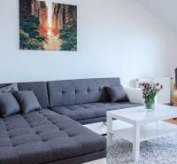 Wohnzimmer mit grauem Sofa, weißem Tisch und Blumen in einer 3-Zimmer-Wohnung.