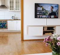 Küche in einer 3-Zimmer-Wohnung mit einem Fernseher an der Wand und Blumen auf dem Tisch.