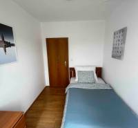 Einfaches Schlafzimmer mit Bett und Holzmöbeln in einer 3-Zimmer-Wohnung.