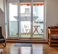 Wohnzimmer mit Balkon, Holzboden, Stuhl und Tisch in einer 3-Zimmer-Wohnung.