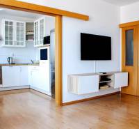 Wohnzimmer in einer 3-Zimmer-Wohnung mit Durchgang zur Küche und Wandfernseher.