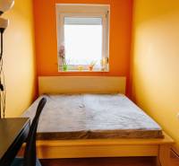 Schlafzimmer mit Bett, Schreibtisch und Fenster in einer 2-Zimmer-Wohnung.