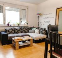 Wohnzimmer in einer 2-Zimmer-Wohnung mit einer Eckcouch und einem Boden in Holzoptik.