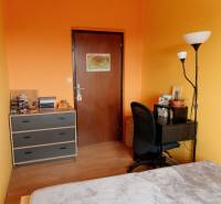 Ein Zimmer in einer 2-Zimmer-Wohnung mit orangefarbenen Wänden, einem Tisch und einem Regal.