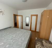 Ein Schlafzimmer mit Bett, Schrank und Spiegel in einem Einfamilienhaus mit Holzboden.