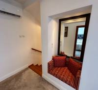 Das Einfamilienhaus zeigt eine Treppe mit Holzdekor, einen Spiegel und eine Sitzecke mit Kissen.