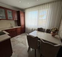 Küche mit dunklen Schränken, weißen Vorhängen und Blumendekoration in einem Einfamilienhaus.