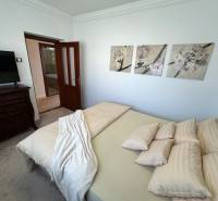 Schlafzimmer eines Einfamilienhauses mit dekorativen Bildern an der Wand, gepolsterten Möbeln und Türen.